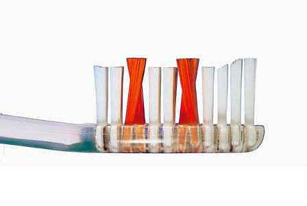 A foto mostra um exemplo de uma escova de dentes com tufos de cerdas de diferentes comprimentos e seu arranjo em forma de X